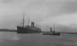 [Liner being manouevered by a tugboat]