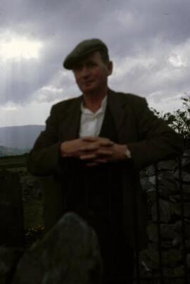 [Farmer leaning on a gate]